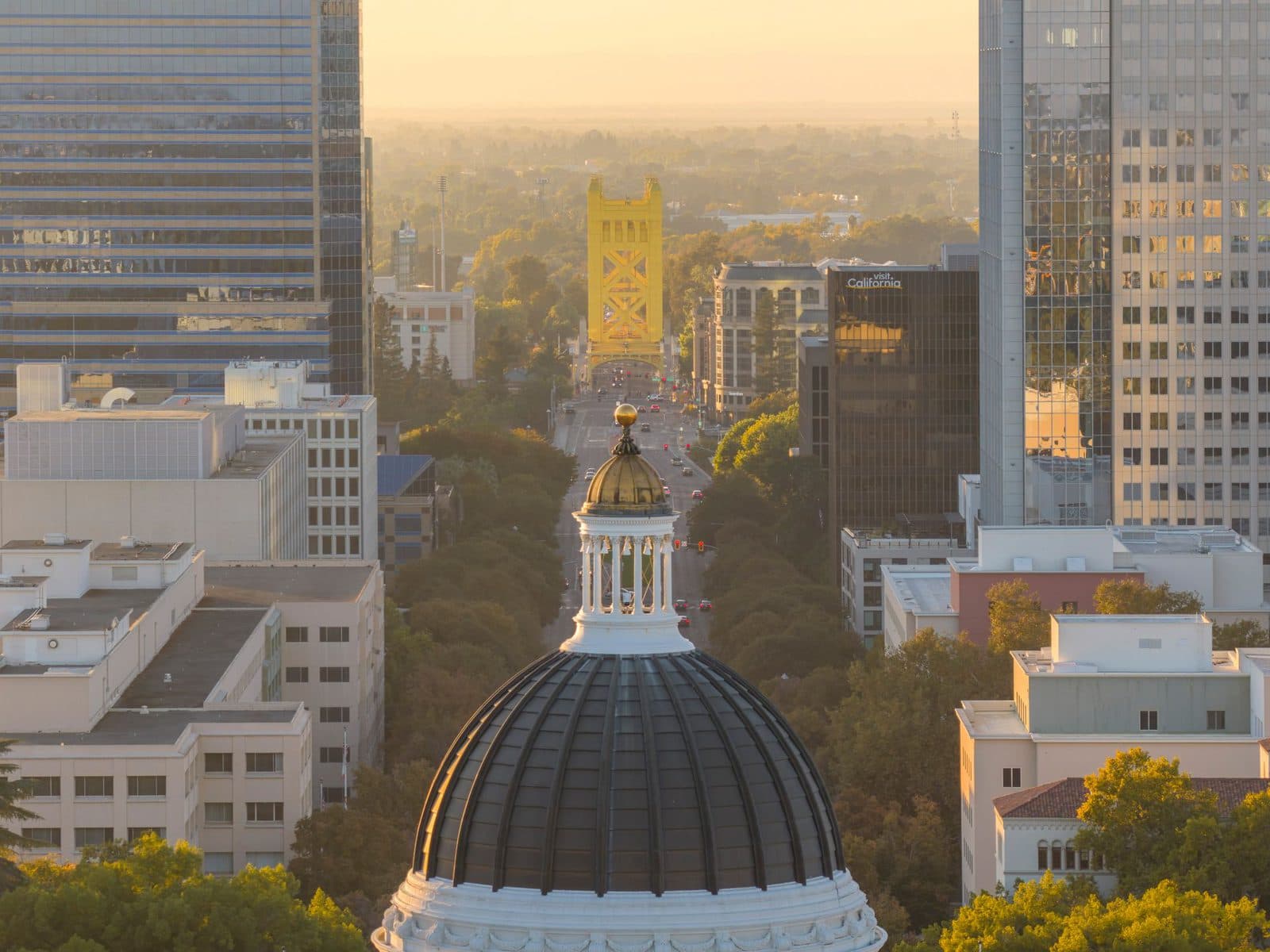 Sacramento skyline at sunset with the California State Capitol dome in the foreground and the Tower Bridge beyond