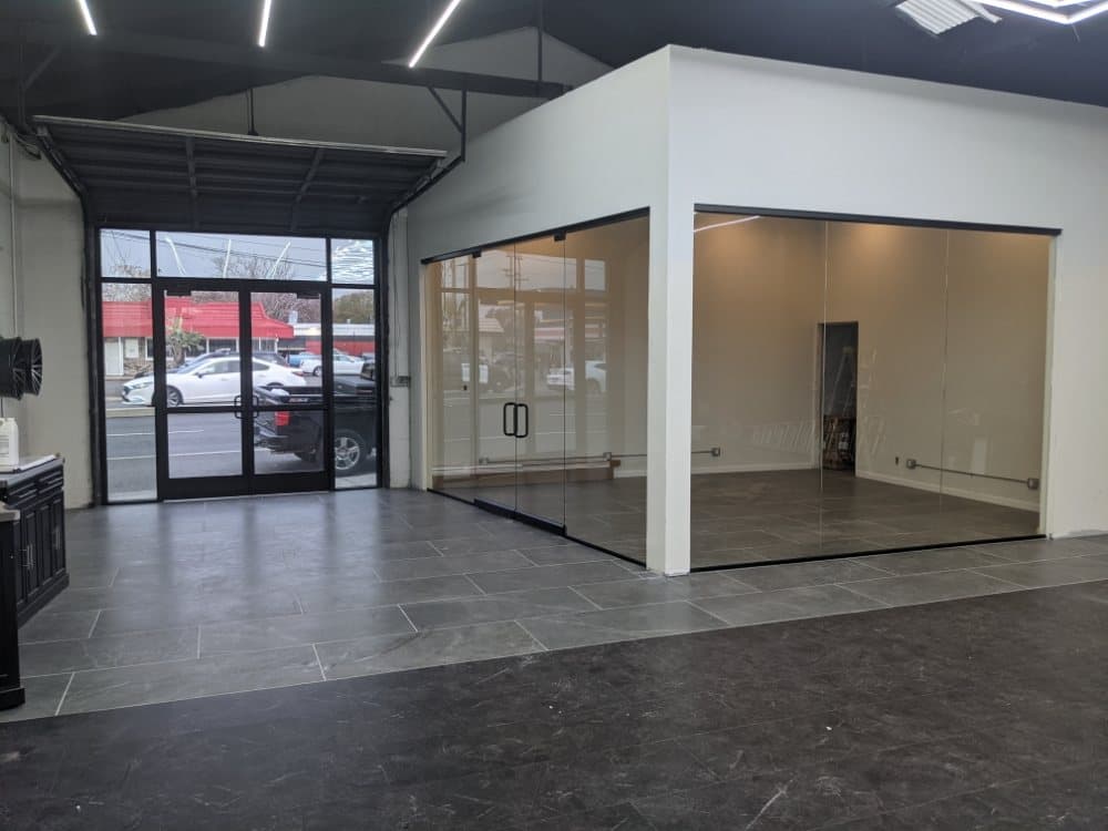 Retail interior with aluminum storefront doors at the street and a frameless glass partitioned room